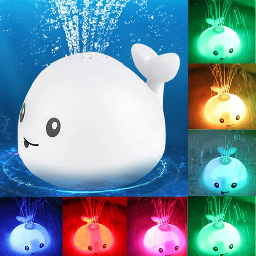 White and blue whale-shaped bath toy spraying water with LED lights on, floating in a baby bath