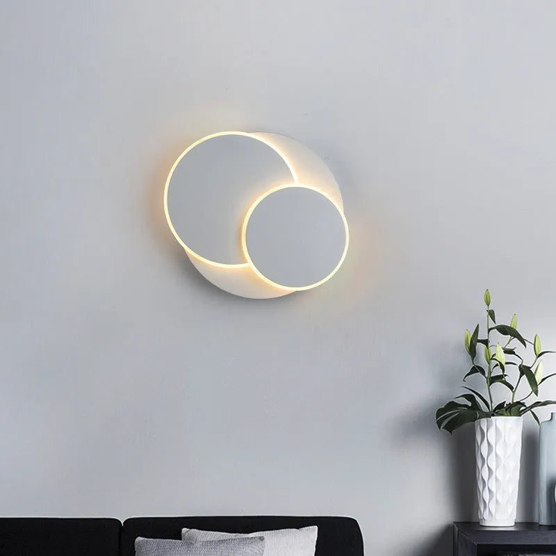 Modern round white acrylic LED wall lamp with push button switch mounted on a wall.