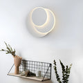 Modern round white acrylic LED wall lamp with push button switch mounted on a wall.