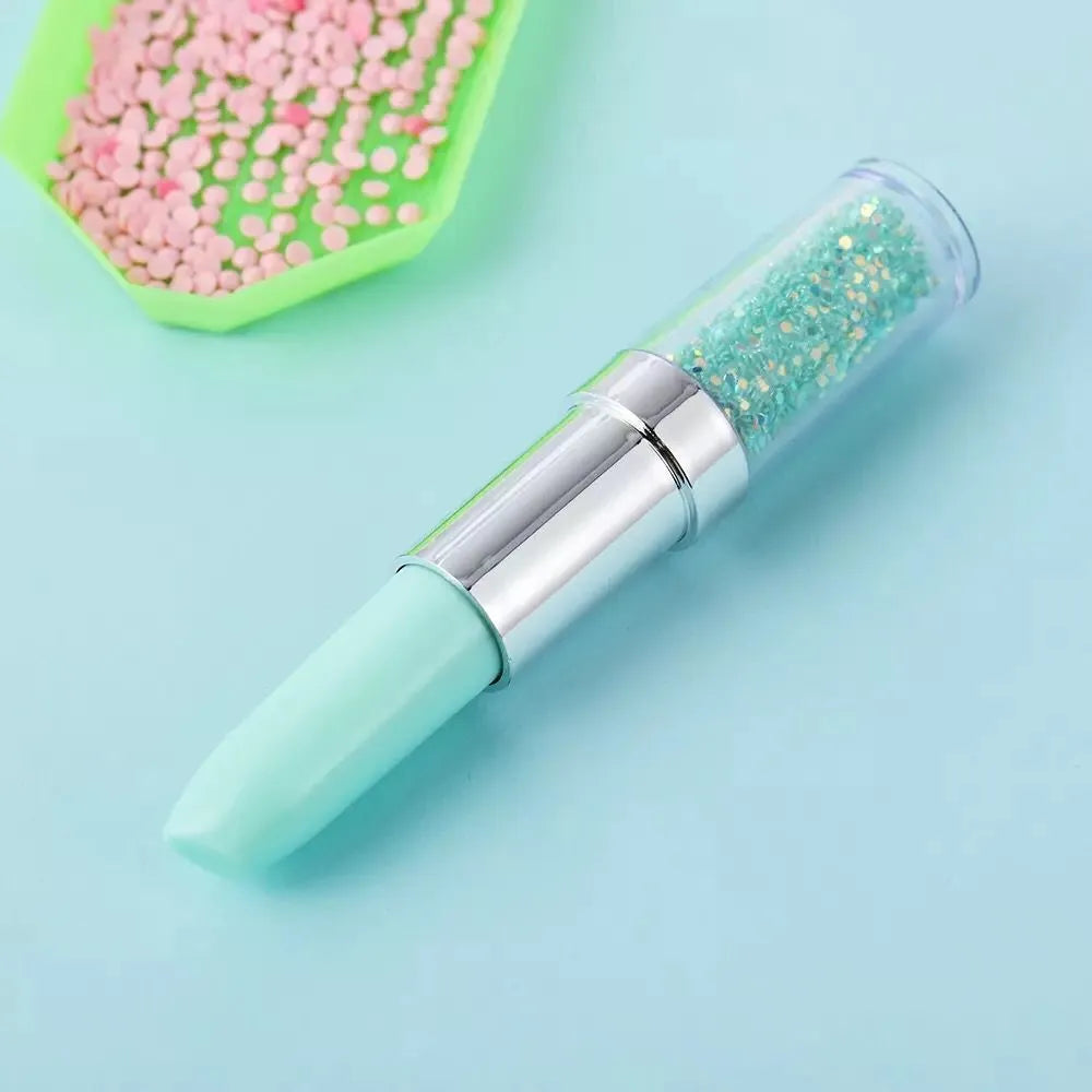 A green plastic point drill pen for diamond painting placed on a craft table.