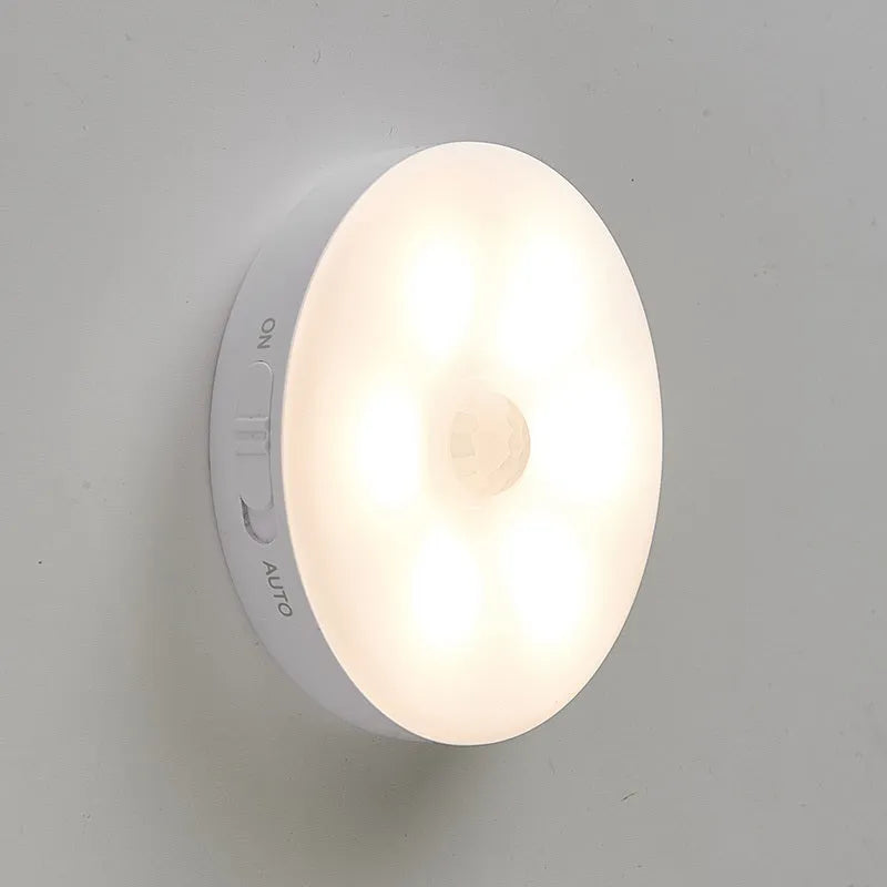 Two small wireless motion-sensor LED night lights placed in a dark hallway.