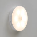 Two small wireless motion-sensor LED night lights placed in a dark hallway.