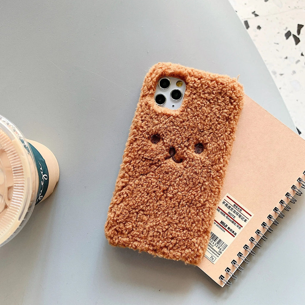 Brown embroidered plush cartoon bear face on a flexible iPhone phone case.