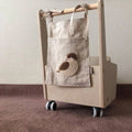 Khaki cotton linen hanging storage bag with multiple pockets mounted beside a bed.