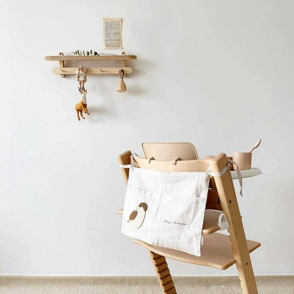 Khaki cotton linen hanging storage bag with multiple pockets mounted beside a bed.