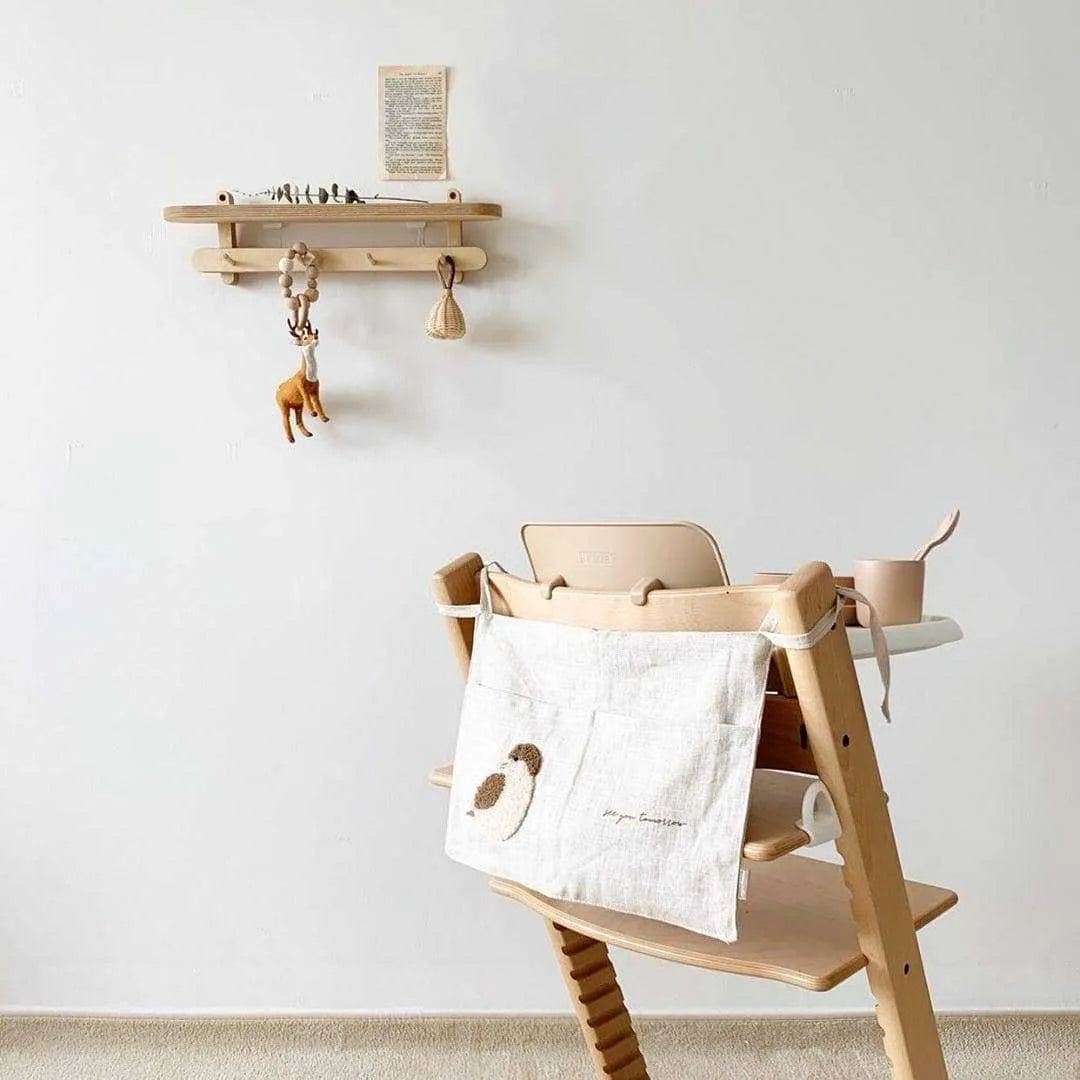 Khaki cotton linen hanging storage bag with multiple pockets mounted beside a bed.
