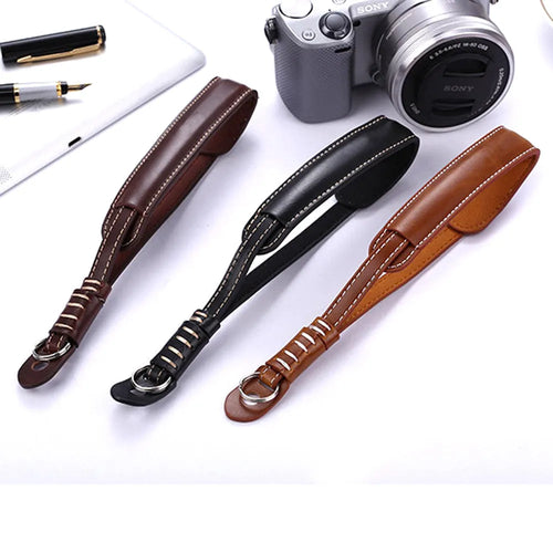 Black leather wrist strap attached to digital camera with small anchor point
