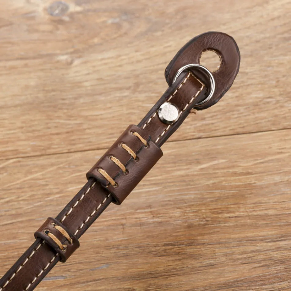 Black leather wrist strap attached to digital camera with small anchor point