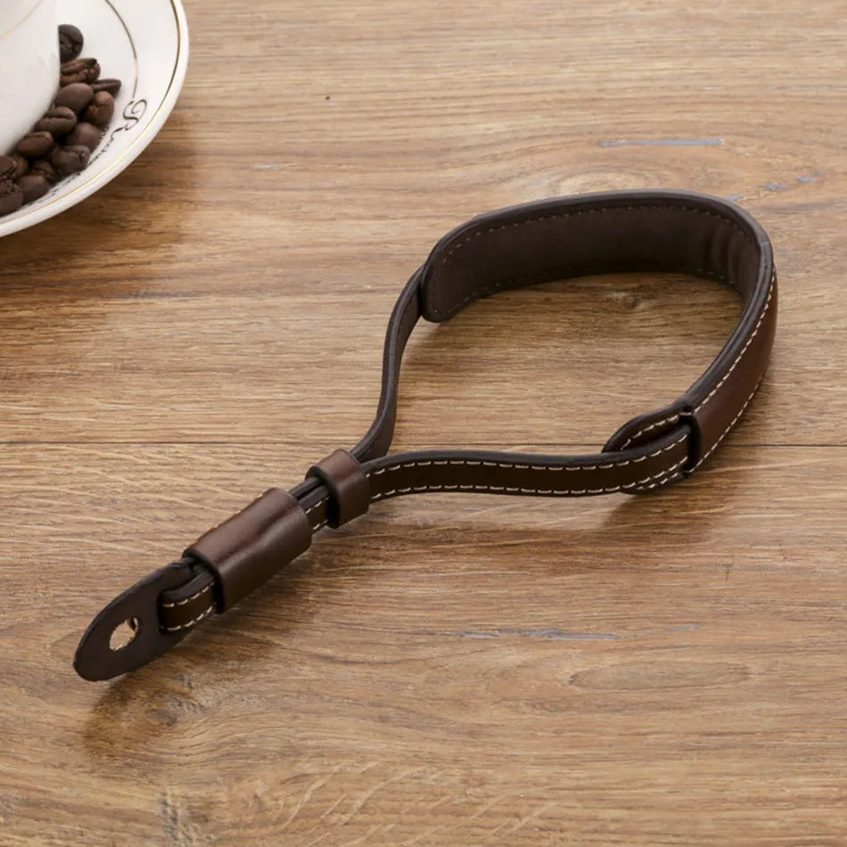 Black leather wrist strap attached to digital camera with small anchor point