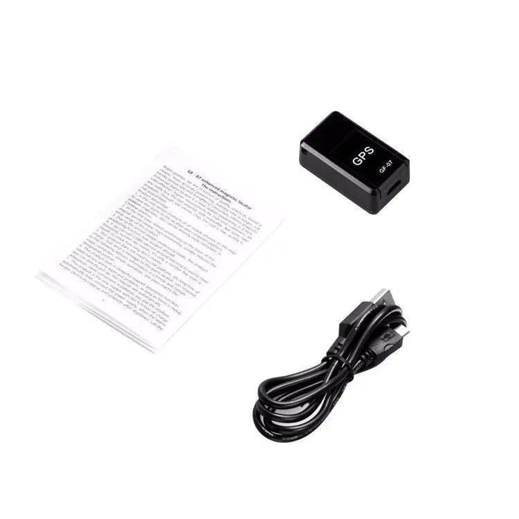 Small black plastic magnetic GPS tracker device next to a USB charging cable.