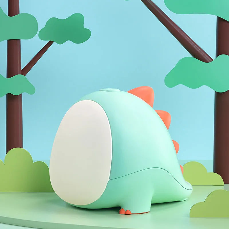 Green dinosaur silicone night light with USB cable, on a bedside table, showing warm light setting