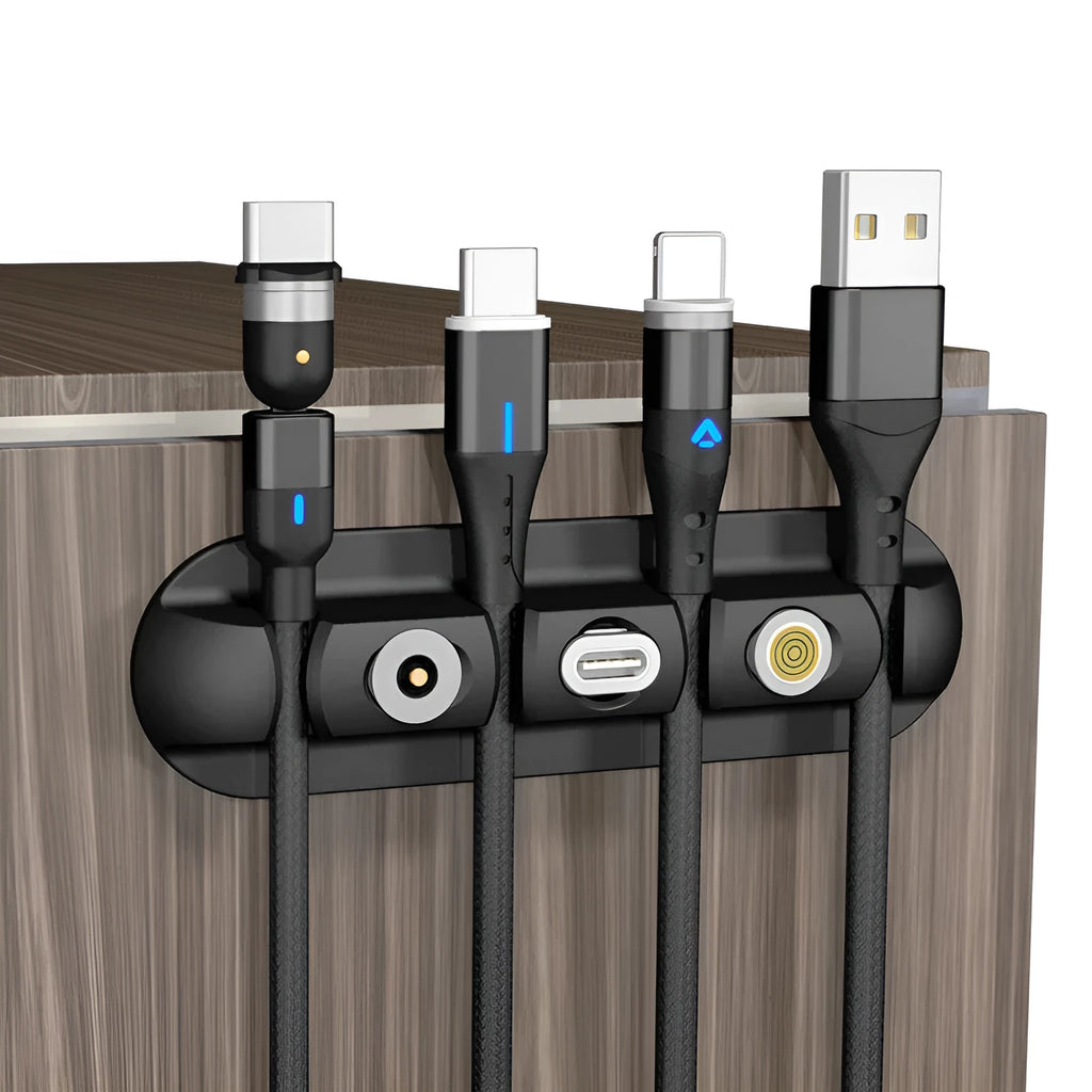 Black soft plastic desktop charging cable organiser on a wooden desk.