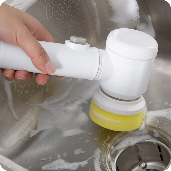 White cordless electric cleaning brush with three interchangeable brush heads on a bathroom sink