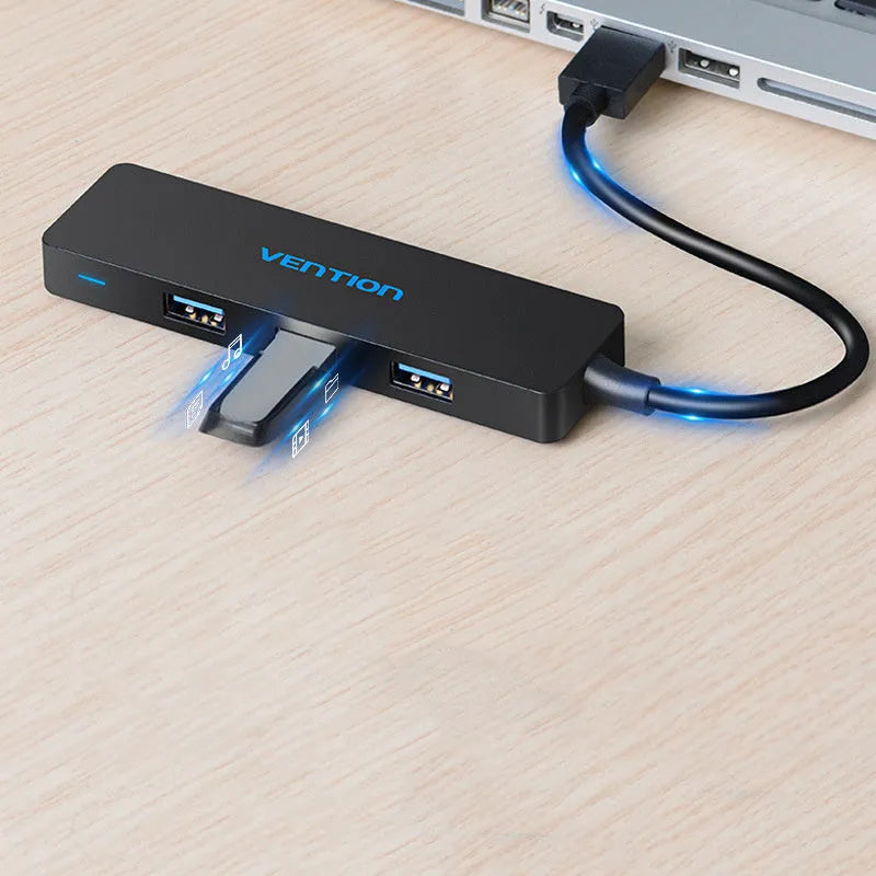 Black four-port USB 3.0 hub with a short attached cable on a desk.