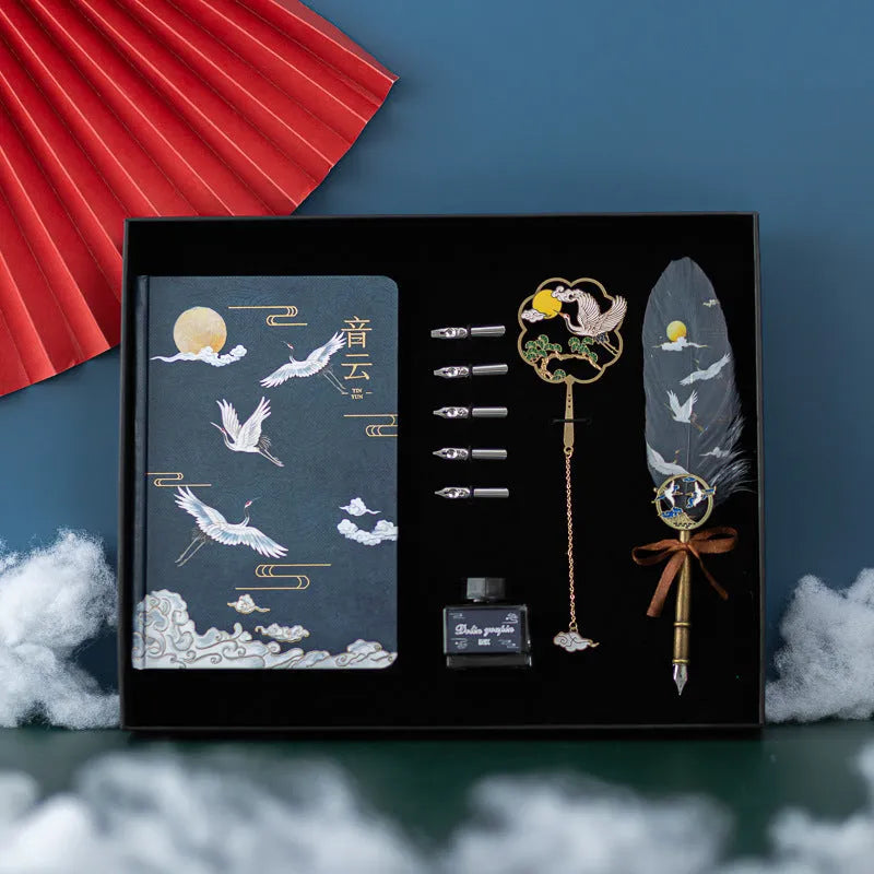 Chinese style metal feather pen with sheath and coloured feather collections next to a notebook.