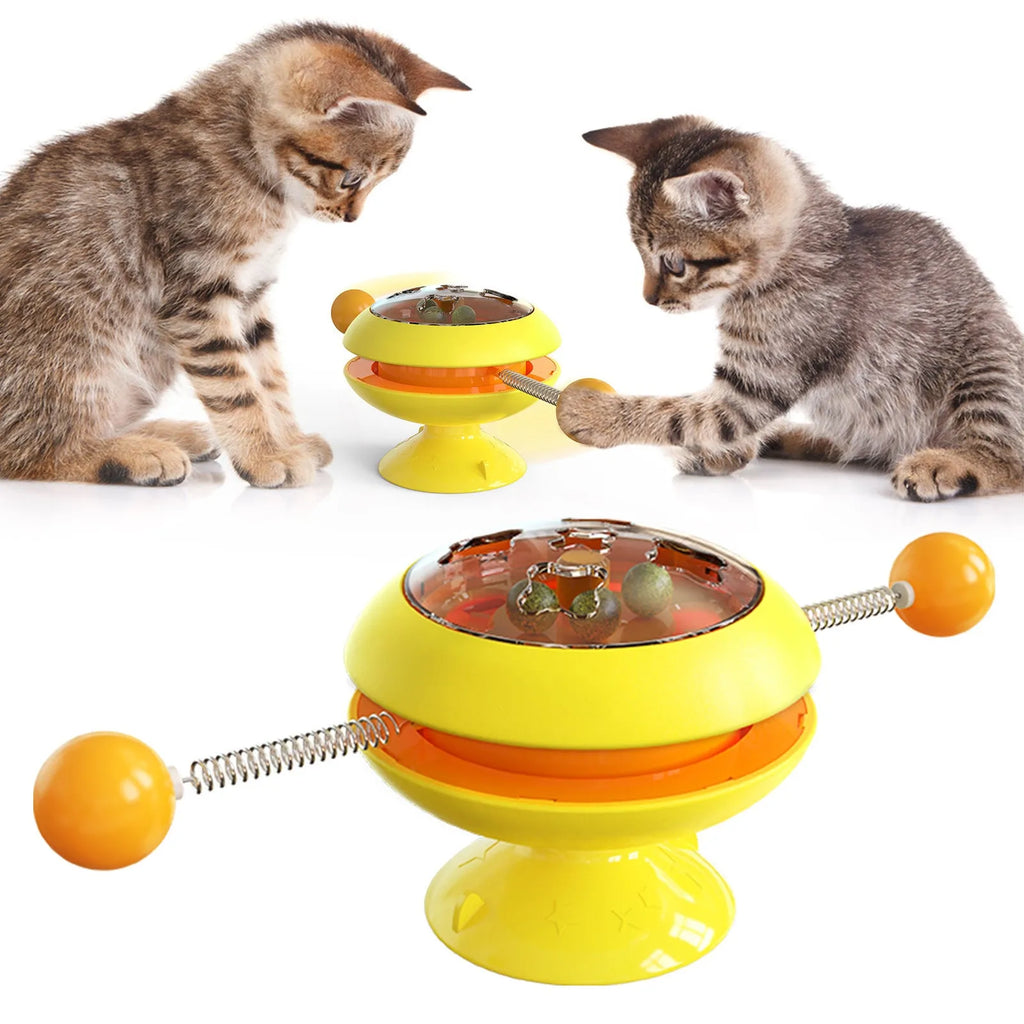 Rotating turntable cat toy with transparent compartment containing catnip balls and suction cup base