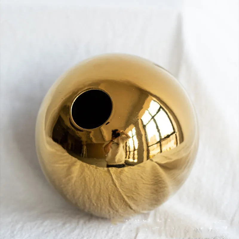 Handmade ceramic gold electroplated spherical vase on a table as home decor