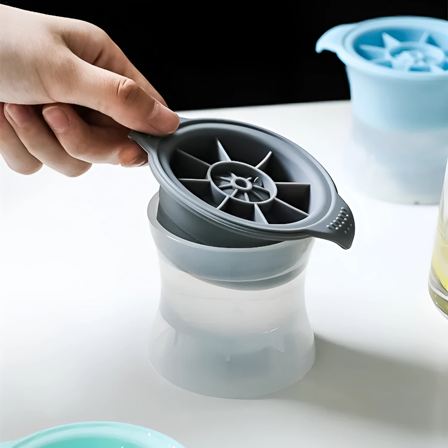 Flexible silicone ice tray producing large hockey puck-shaped ice cubes and other decorative shapes like spheres and pentagons.