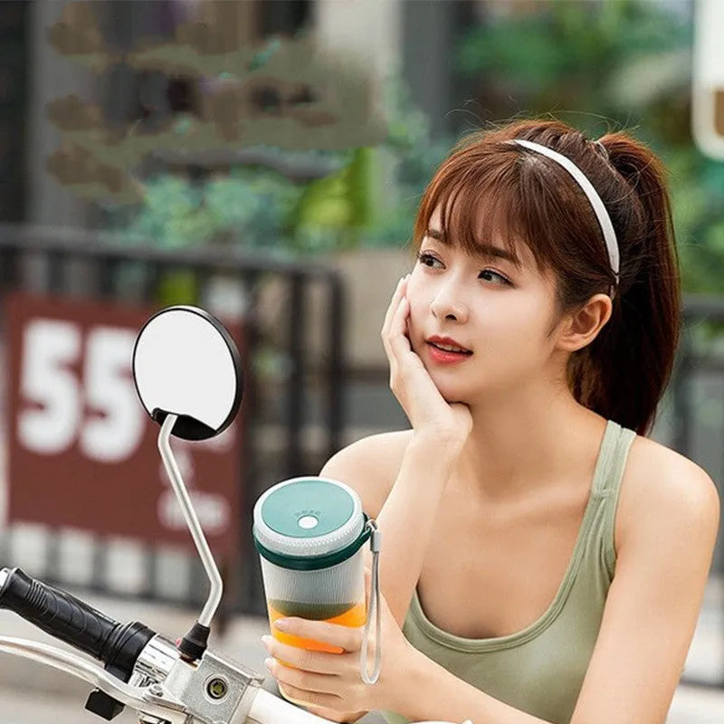 Small pink and green portable electric juicer cup with USB charging cable.