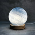 Nordic style USB table lamp with a glass shade shown in a choice of colours on a bedside table.