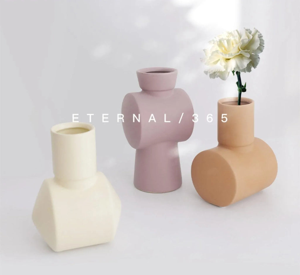 Hammered ceramic vase in a soft Morandi colour glaze on a wooden surface.