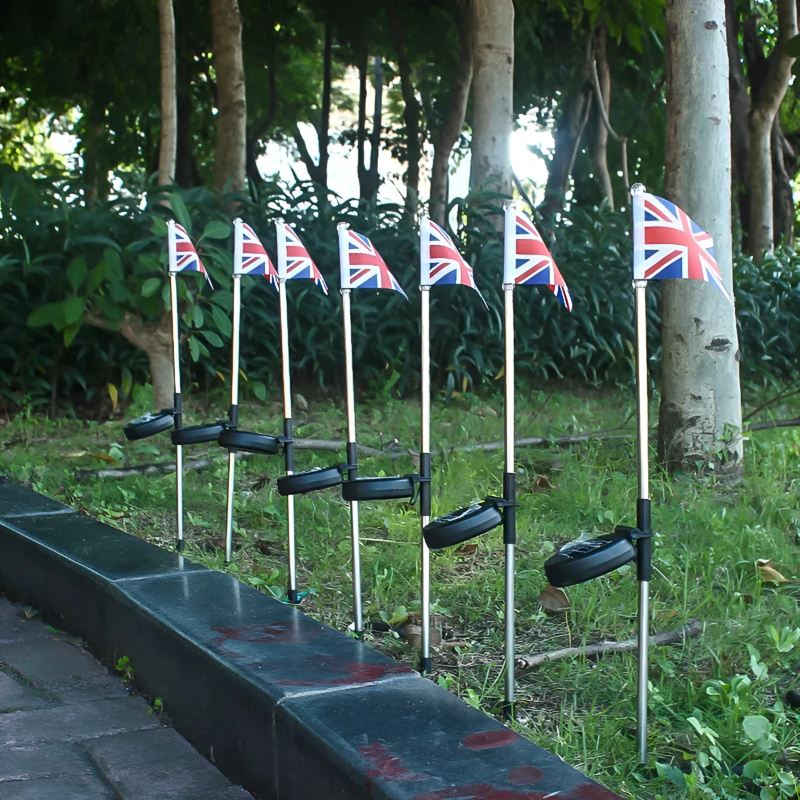 Solar-powered stainless steel garden flag light showing American flag design with white LEDs illuminated.