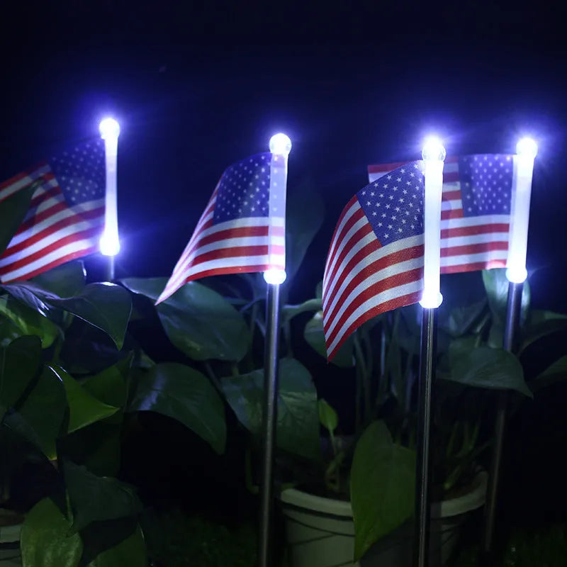 Solar-powered stainless steel garden flag light showing American flag design with white LEDs illuminated.