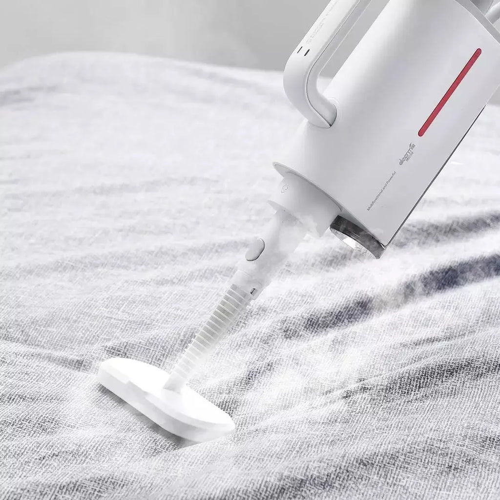 Deerma DEM-ZQ610 white steam cleaner main unit with brush heads, glass scraper, and mop attachments on a table.