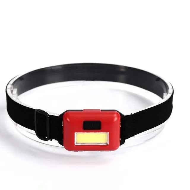 Small blue outdoor LED headlight with adjustable polyester strap on a dark background.