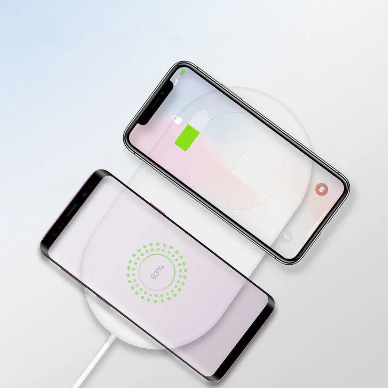 A simple white dual wireless charger for two mobile phones on a desk.