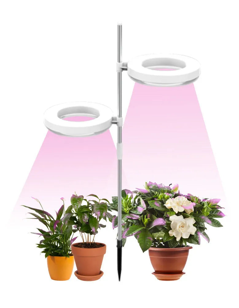 Compact white full spectrum plant growth lamp on a desk next to indoor greenery.
