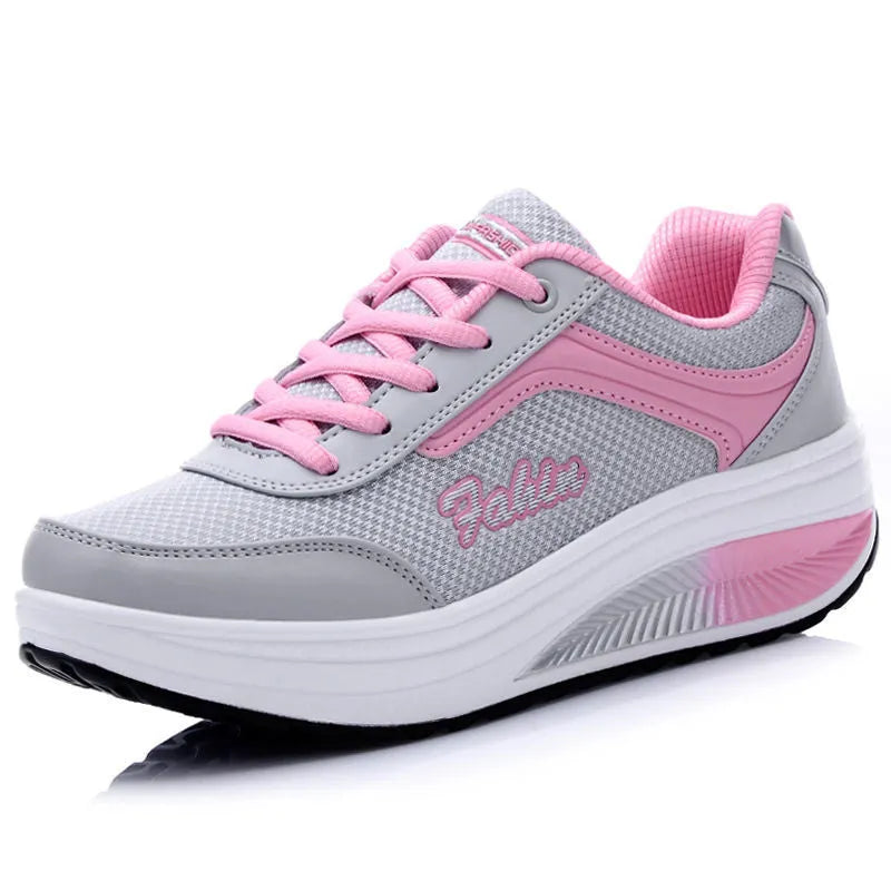 Women's grey powder heelless sports shoes with a middle heel on a plain background.
