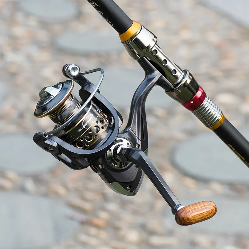 Telescopic carbon fibre fishing rod with spinning reel, solid wood handle, and metal wire cup on a rocky shore