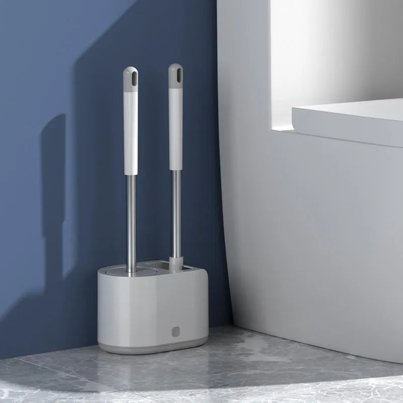 White silicone toilet brush set with long handle, soft TPR head, and second cleaning brush on a bathroom floor