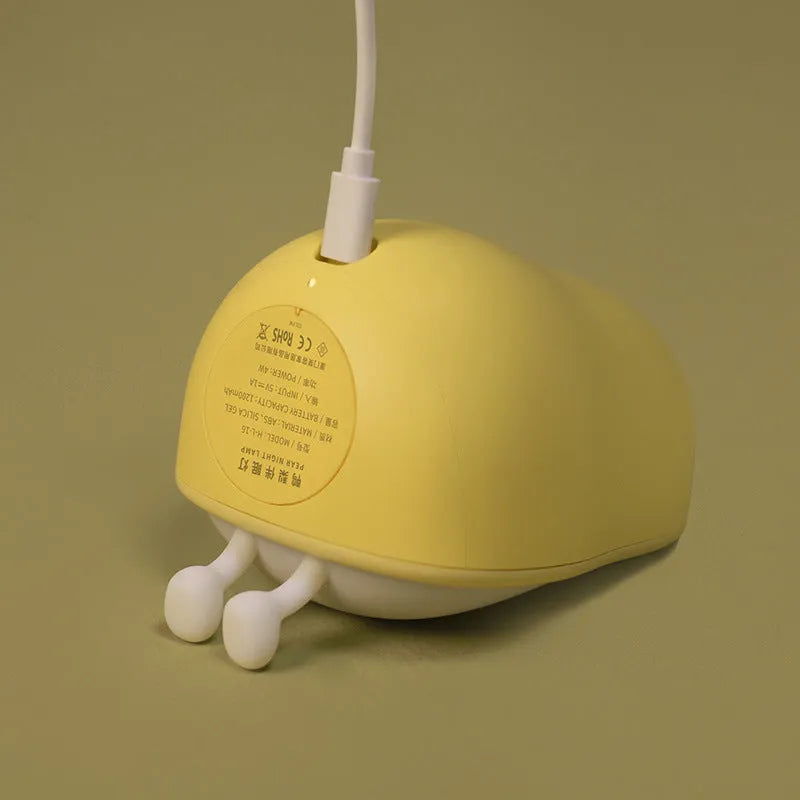 Yali pear-shaped silicone night light with warm yellow illumination on bedside table