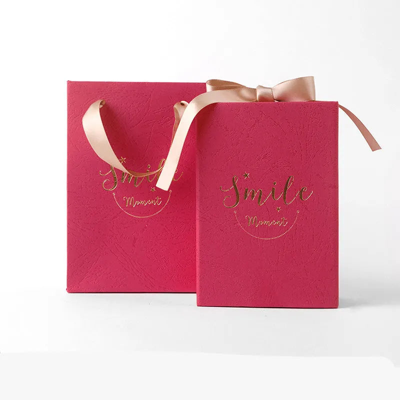Small cardboard gift box with bronzing detail, handbag, and raffia tie in blue colour