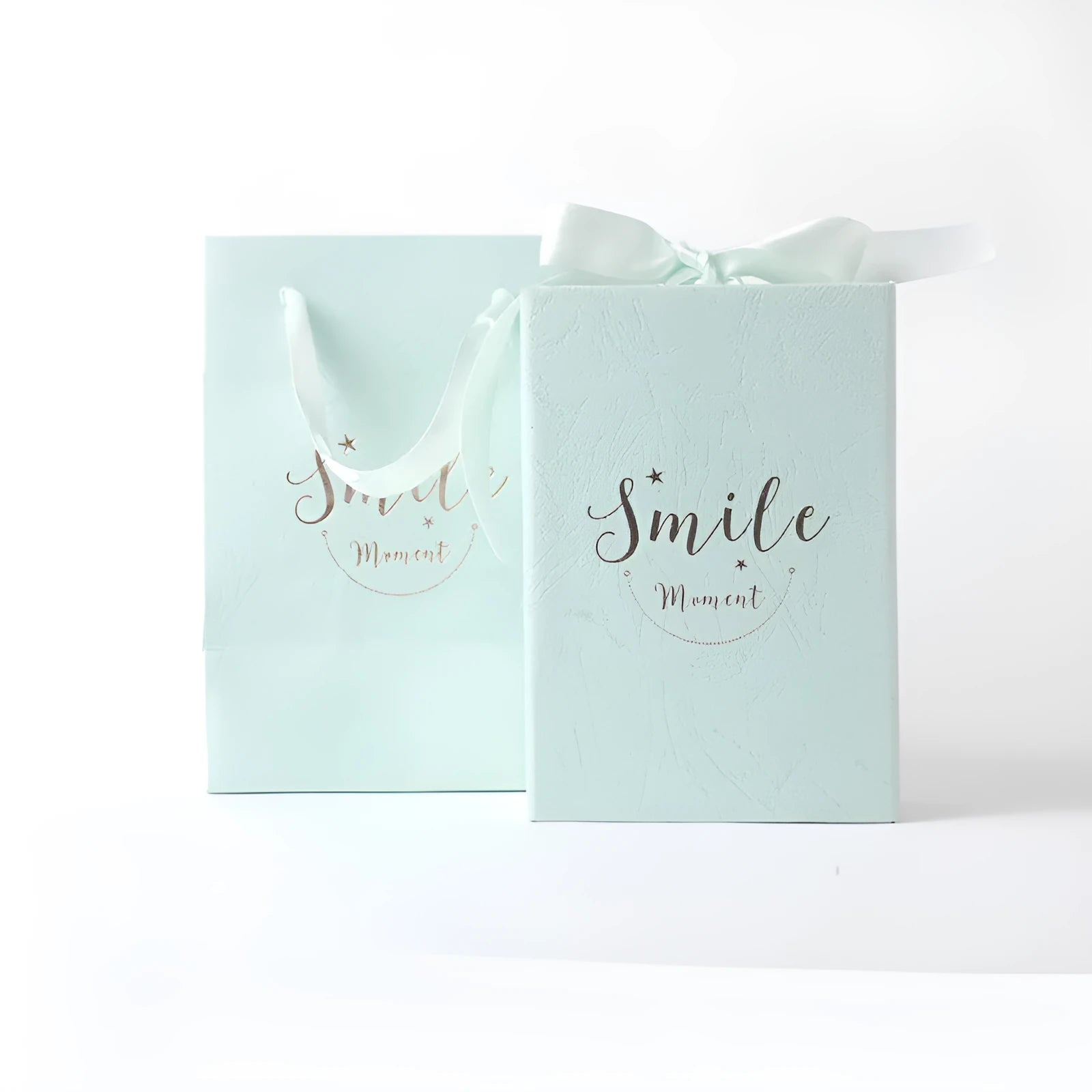 Small cardboard gift box with bronzing detail, handbag, and raffia tie in blue colour