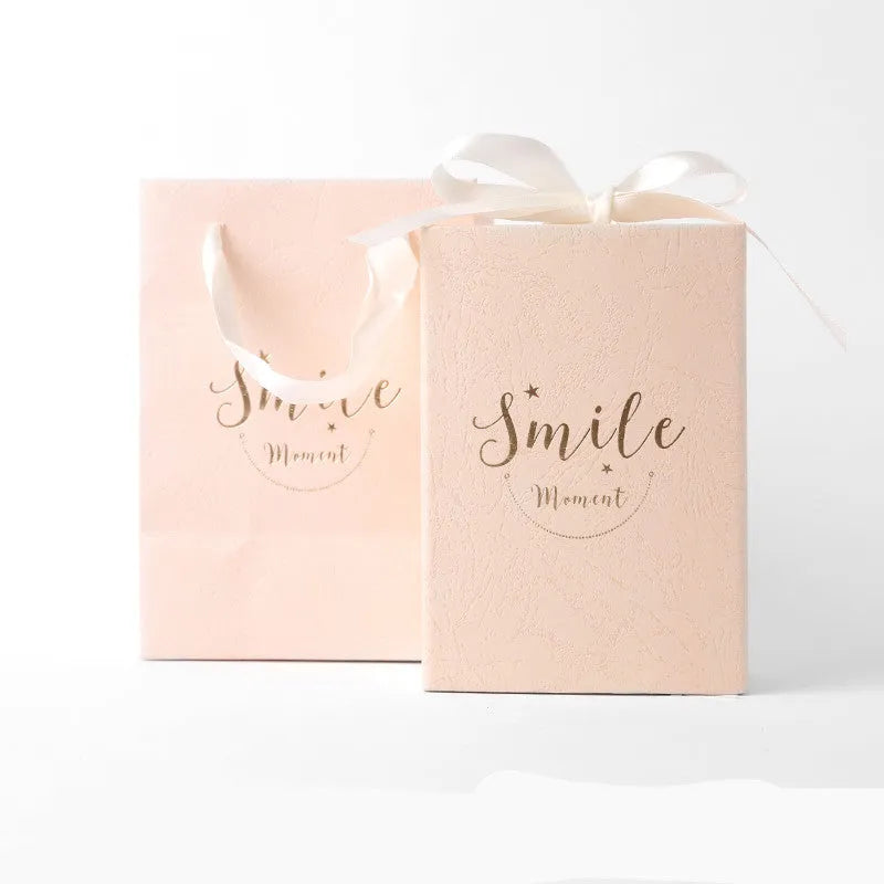 Small cardboard gift box with bronzing detail, handbag, and raffia tie in blue colour