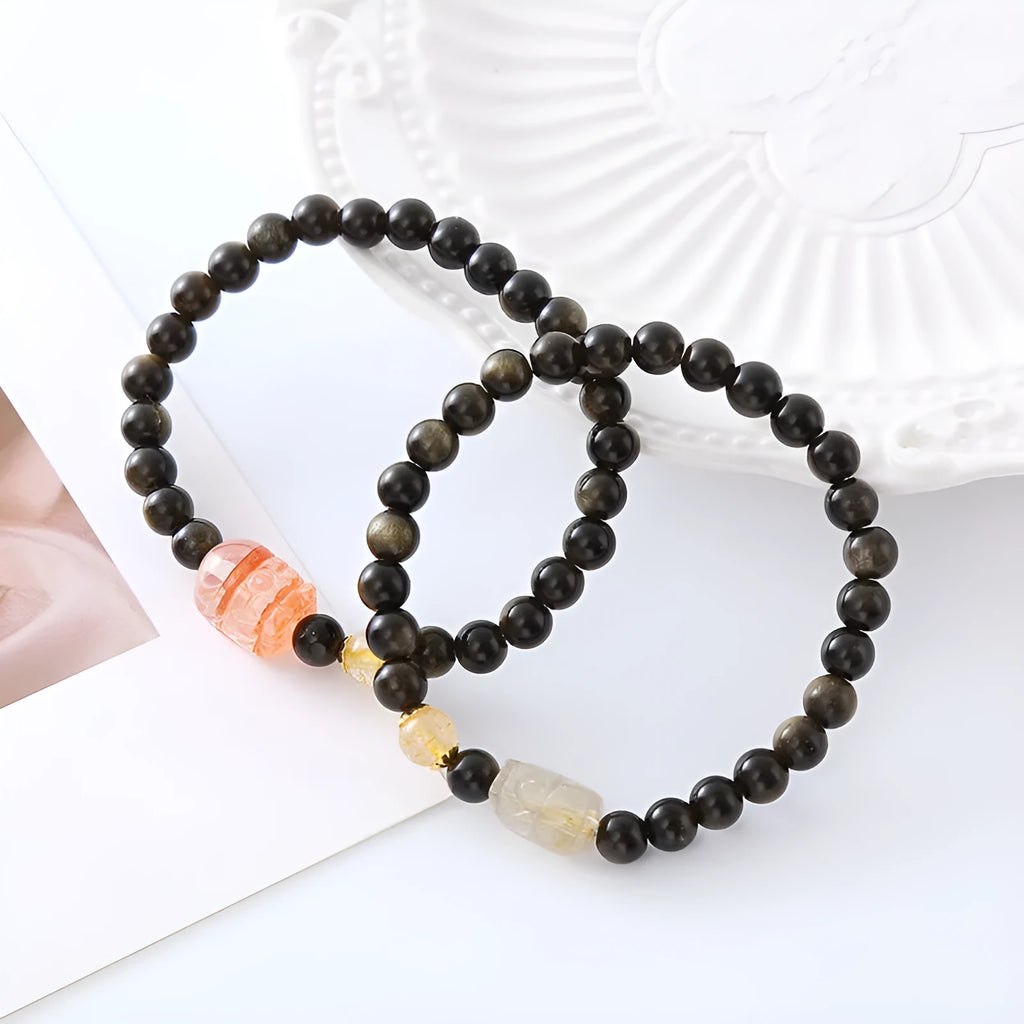 Handmade gold obsidian and red flower bead Pi Xiu bracelet on wrist, ethnic retro style.