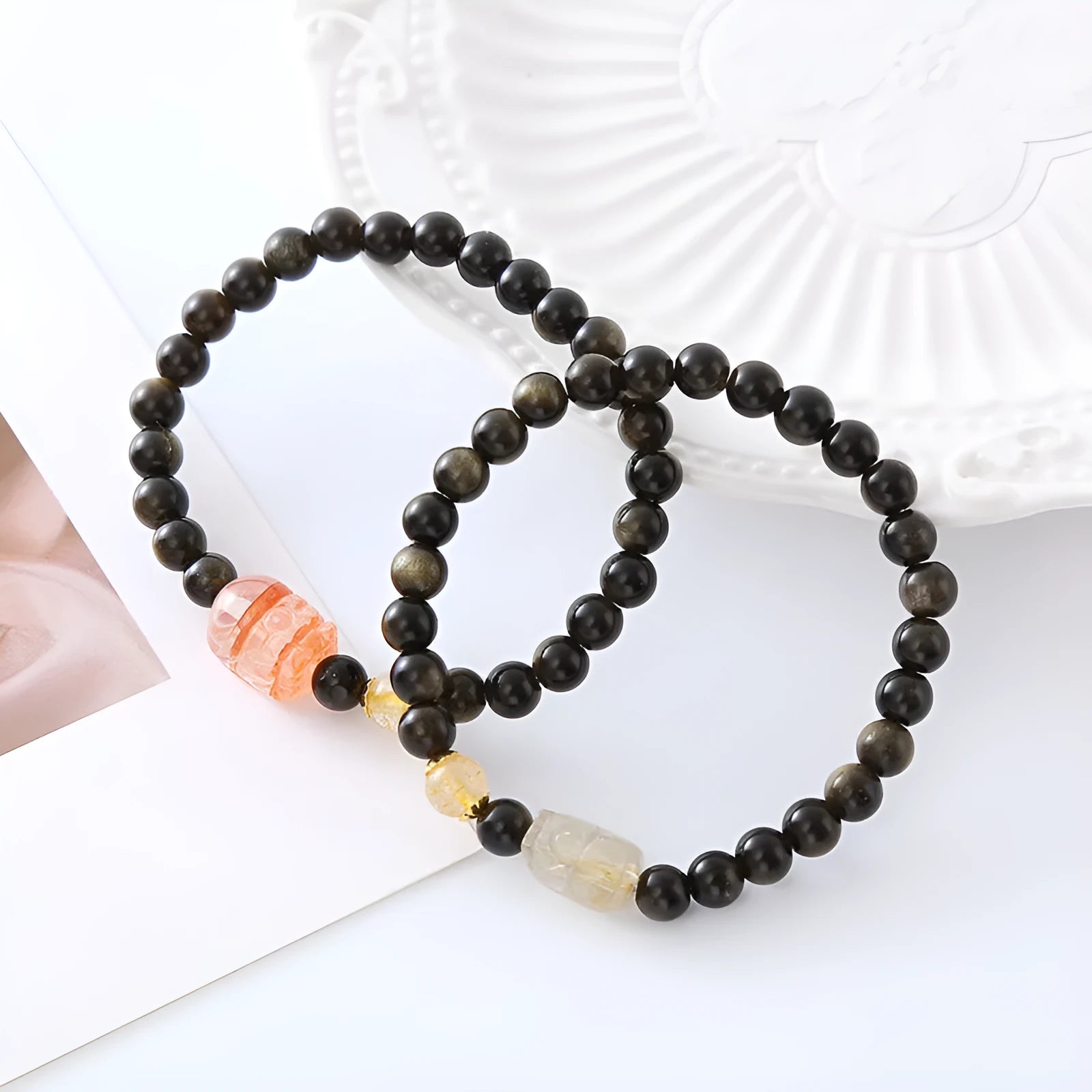 Handmade gold obsidian and red flower bead Pi Xiu bracelet on wrist, ethnic retro style.