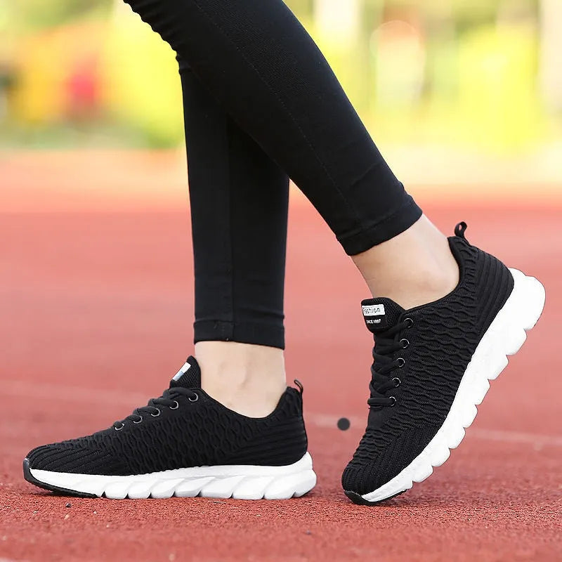Women's running shoes in black, pink, or white with a fly-weave upper and durable outsole.