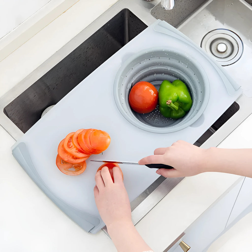 Grey 3-in-1 chopping board with detachable folding drain basket on a kitchen counter.