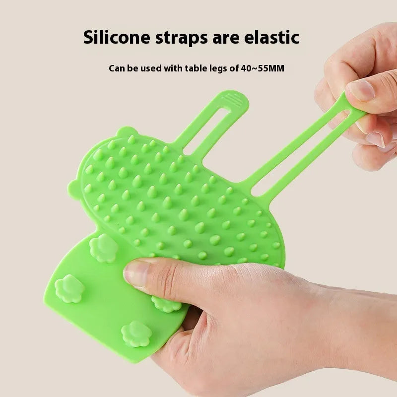 Black silicone cat grooming brush with comb teeth and an adjustable mounting strap.