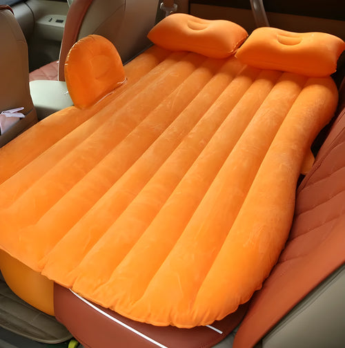 Inflatable car bed with flocked surface folded beside two pillows in storage bag for vehicle sleeping
