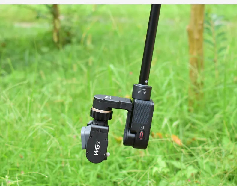 Black retractable aluminium selfie stick extended with phone attached, showing Bluetooth remote and tripod stand.