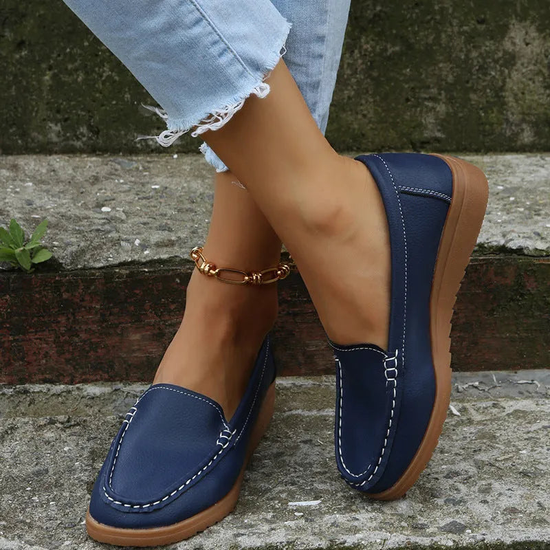 Women's black PU leather flat loafers with round toe and car suture design on a rubber sole.