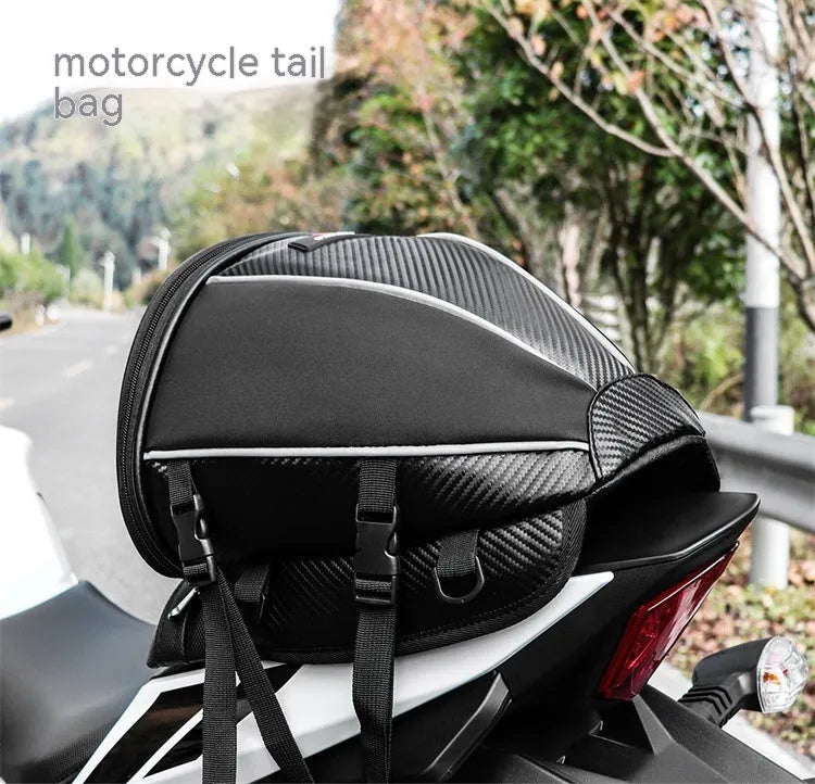 Black motorcycle seat bag with reflective strips, showing multiple pockets and an adjustable shoulder strap.