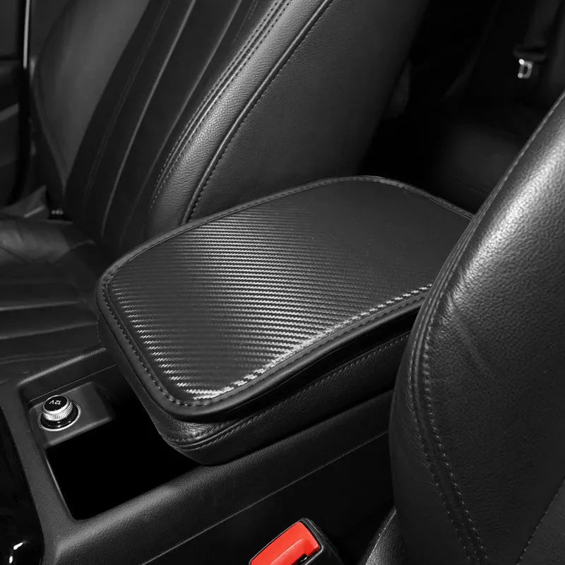 Carbon fibre pattern leather car armrest cushion mat in black, shown on a car centre console.