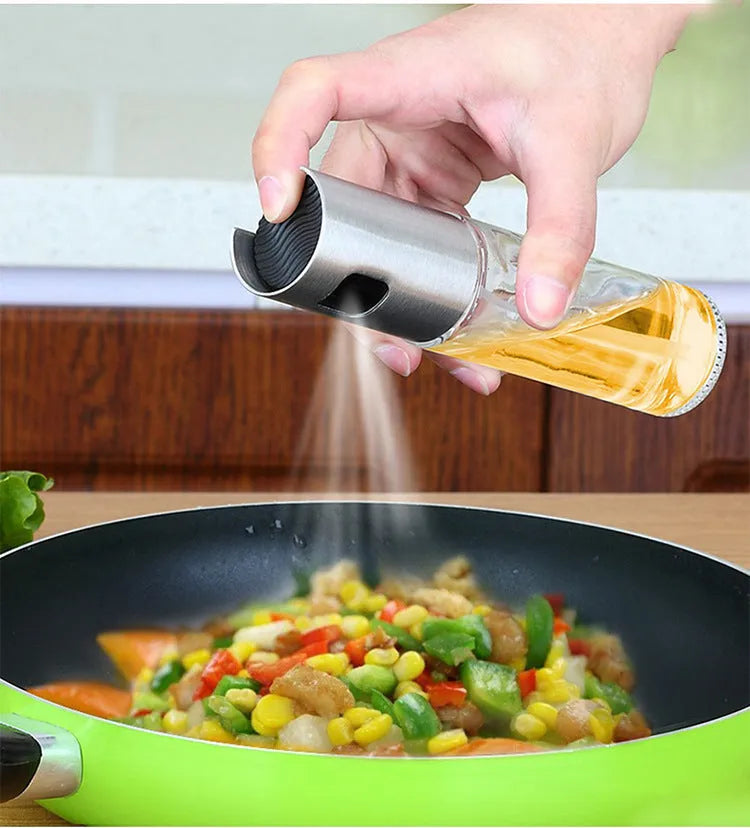 Gold pump-action oil and vinegar spray bottle with 100ml glass body on kitchen counter.