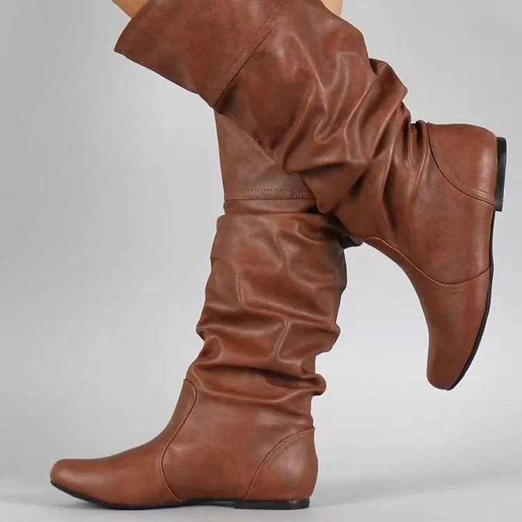 Women's black slip-on flat boots with a round toe and high cylinder shaft, showing the rubber sole.